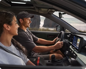 A driver and passenger in the front seats of a Toyota SUV on a country road