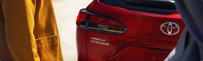 Close-up of the Corolla Cross badge on the liftgate of a red Toyota Corolla Cross