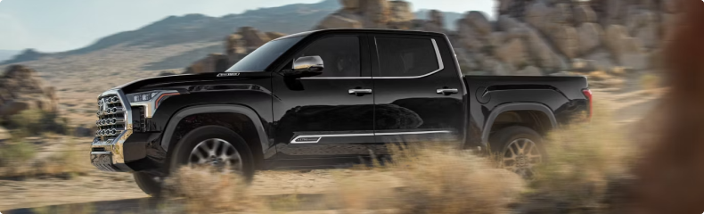 A black Toyota Tundra in profile driving through open rocky desert country