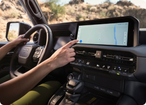A driver reaching for the navigation map on a Toyota touchscreen
