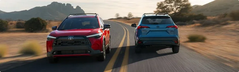 A red and a blue Toyota Corolla Cross passing each other on a desert highway