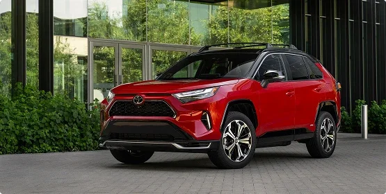 Red Toyota RAV4 Prime plug-in hybrid parked outside a glass-walled building