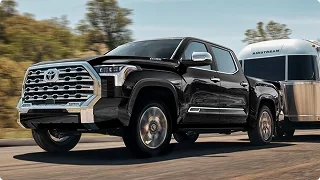 Black Toyota Tundra towing a silver travel trailer on a country road