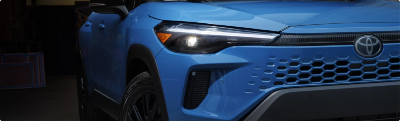 Close-up of the LED headlight and grille on a blue Toyota Corolla Cross Hybrid