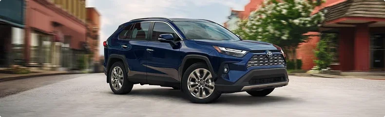 A dark blue Toyota RAV4 driving down a small town main street