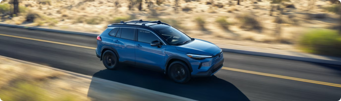 Blue 2026 Toyota Corolla Cross Hybrid driving on a desert highway