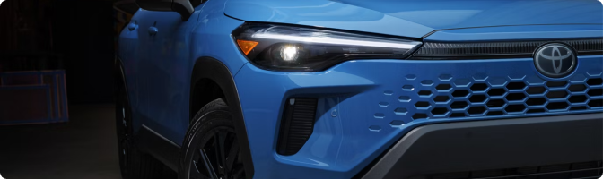 Close-up of the LED headlight and grille on a blue 2026 Toyota Corolla Cross Hybrid