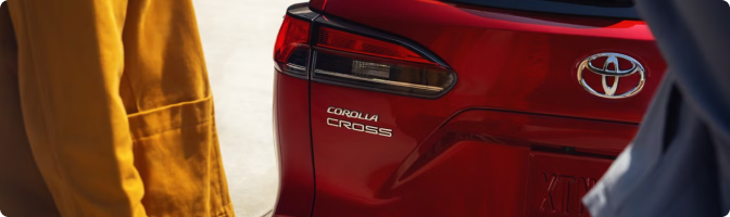 Close-up of the Corolla Cross badge and taillight on a red 2026 Toyota Corolla Cross