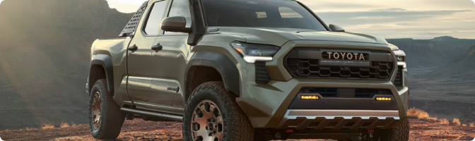 Green 2026 Toyota Tacoma Trailhunter parked on a ridge at sunset