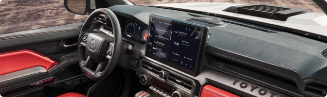 2026 Toyota Tacoma dashboard with the 14-inch touch screen and red interior trim