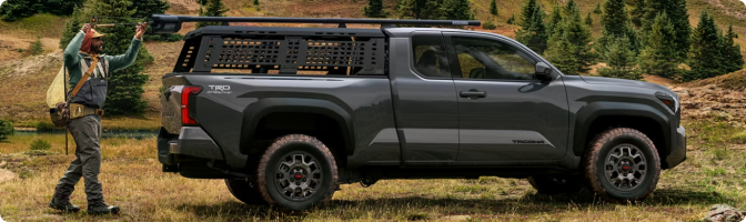 Gray 2026 Toyota Tacoma Trailhunter with a bed rack parked in a mountain meadow