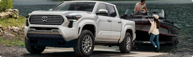 White 2026 Toyota Tacoma Limited at a lake boat launch with a boat behind it